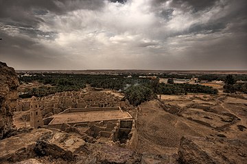 Ruins of a desert oasis town with palm groves in the backround