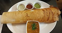 Dosa with chutney and sambar with sauteed potato filling in a restaurant