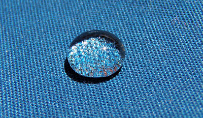 A shiny spherical drop of water on blue cloth