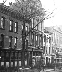 The Washington Street entrance shortly after the fire. A crowd has congregated in front of the First Precinct station house, one door south, possibly to inquire after missing people or to file reports Brooklyn Theatre After Fire Washington Street.jpg