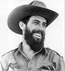 Portrait photograph of Camilo Cienfuegos, smiling while wearing a beard and a Stetson hat