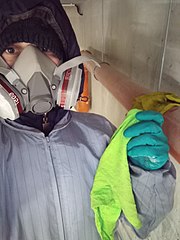 Cleaning a building in mask, overalls and gloves to prevent exposure to dust.