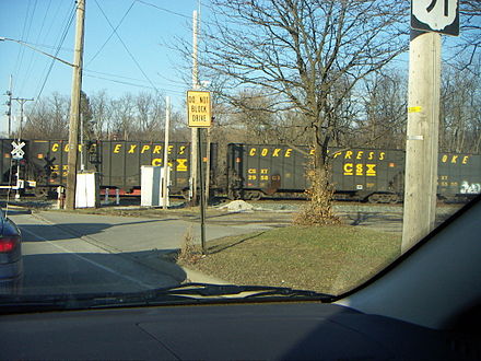 The Coke Express rolls through a level crossing. Hopper cars display both the CSX logo and the words COKE EXPRESS