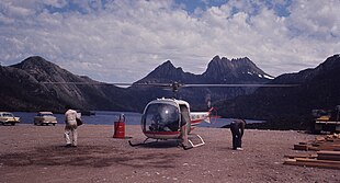 Helikopter ve iki kişi, arka planda dağlar