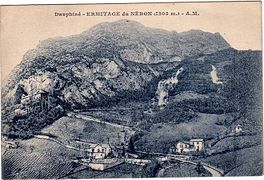 Antigo cartão postal com algumas construções, incluindo um castelo no sopé de uma montanha, com uma estrada sinuosa por vinhedos.