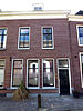 Dubbel woonhuis, drie bouwlagen, grauwe bakstenen lijstgevel, dakkapel met fronton, kroonlijst en schilddak (Gouda-Centrum)