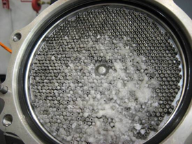 Heat exchanger. Circular latticework with an uneven covering of small particles over part of its surface.