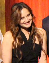 A 31-year-old woman with brown hair smiling to the right of the camera.