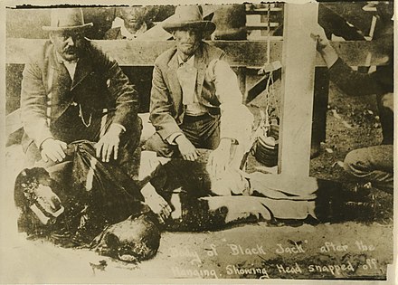 Sepia-tone photo from a contemporary 1901 postcard showing Tom Ketchum's decapitated body. Caption reads "Body of Black Jack after the hanging showing head snapped off."