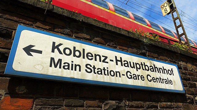 A Deutsche Bahn sign giving directions in three languages to Koblenz Hauptbahnhof.