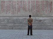 A man reading the text at the base of the Juche Tower