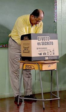 Luis Guillermo Solis, then-President of Costa Rica, votes behind a privacy screen which says "The VOTE is SECRET". Luis Guillermo Solis, elecciones abril 2014.jpg