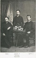 מימין: מנחם מנדל דוליצקי, לאון רבינוביץ (עומד) ויעקב מזא"ה, 1885. על השולחן תמונתם של פרץ סמולנסקין ואחרים