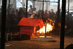 A heavyweight rumble from RoboGames 2007, featuring Red Baron (a dog house-themed robot with a flamethrower), Megabyte (a silver full-body spinner), Mulch (a black boxy robot), and Little Blue Engine (a blue four-wheeled rammer) Robot combat with flame.jpg