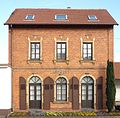 Der ehemalige Bahnhof Saarlouis-Lisdorf von 1897 mit französisch inspirierten Stilelementen wie Fenstereinfassungen aus Natursteinen, die dennoch die für Vering & Waechter typischen Segment- und Rundbogenfenster erkennen lassen.