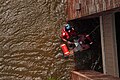 A Coast Guard Aviation Survival Technician assisting with the rescue of a pregnant woman during Hurricane Katrina in 2005