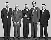 Five men wearing suites stand side by side