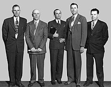 Five men wearing suites stand side by side