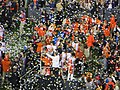 English: Clemson is presented with the CFP trophy after winning the 2019 College Football Playoff National Championship. I believe the coach is being interviewed, but there's too much confetti to tell.