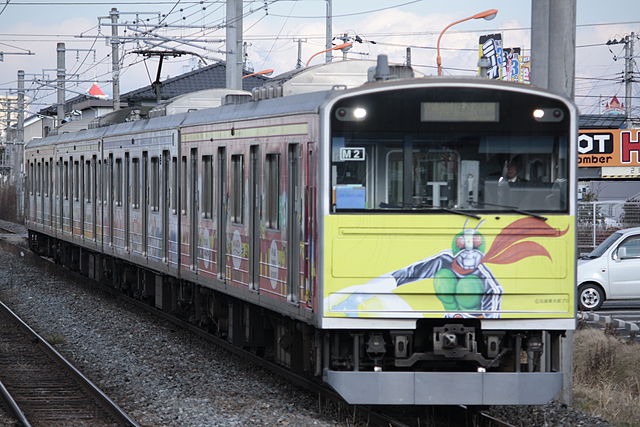 A 205 series train on the Senseki Line with Kamen Rider and other Shotaro Ishinomori character livery. The Senseki Line has a terminal in Ishinomori's