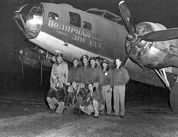 A B-17 crew poses with their plane. The nose art on the bomber reads "Polar Star" (likely referring to the star Polaris) in Russian.