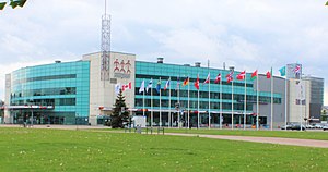 Arena exterior clad in white and turquoise siding with three floors of glass windows, including a green area with flags of countries participating in the 2006 International Ice Hockey Federation World Championship.