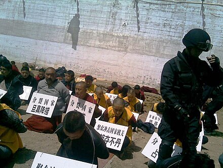 Tibetans arrested by Chinese authorities. The signs list their crime and their name.