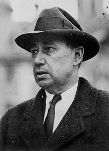 Photo of Austin dress in outdoor business attire: a Homberg-style hat, white business shirt and tie, and a winter coat.