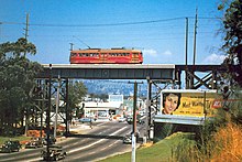 a red train crossing above a street on a concrete bridge