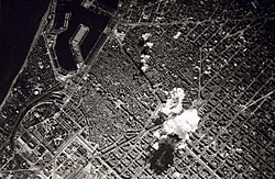 تصویر سیاه و سفید از بالا، دود انفجار بمب قابل مشاهده‌است.