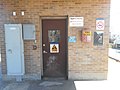 The western door of the waiting room. Note the alarm keyboard, the braille sign and Police and Fire Department emergency phone,