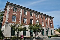 Three-storey brick building with tall arched windows on the ground floor and rectangular windows on the first and second floors