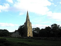 A stone church with a tower and spire, seen from the southwest