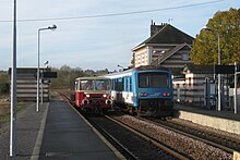 Ansicht eines Triebwagens, der einen Triebwagen mit Ausrüstung in einer Station kreuzt