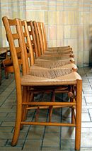 A row of brown, wooden chairs with a seat made of some woven material