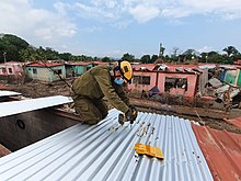 A man repairs a roof on a damaged house.