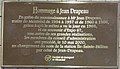 "Teyrnged i Jean Drapeau i gydnabod Me Jean Drapeau, maer Montreal o 1954 i 1957 ac o 1960 i 1986, diolch i bwy y crëwyd y metro ym 1966, ac er cof am Expo 67, un arall o'i lwyddiannau mawr, aelodau o aeth bwrdd y cyfarwyddwyr ymlaen, ar 10 Mai 2000, i newid enw gorsaf Île-Sainte-Hélène i enw Jean-Drapeau. Cwmni Transit Montreal"