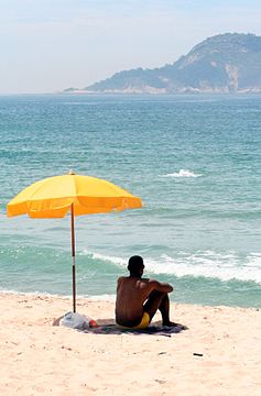 "Man_sitting_under_beach_umbrella.JPG" by User:Sir James