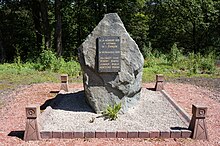 Un rocher entouré de quatre mini chevalement en béton porte une plaque de marbre. Inscription : À la mémoire des 4 victimes de l’étançon le 16 décembre 1950, Billequey Louis, Demesy martial, Jenroy Marius et Kortitzko Gerard.