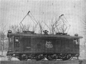 Boxy locomotive with two pantographs raised to contact overhead lines