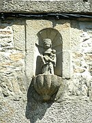 Photographie d'une statuette en pierre dans une niche de façade.
