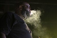Rick Ross recorded his verse for "Devil in a New Dress" within a very close proximity from when the album had to be turned in to the record label. Rick Ross The Mastermind Tour June 15, 2014 Toronto (14426793450).jpg