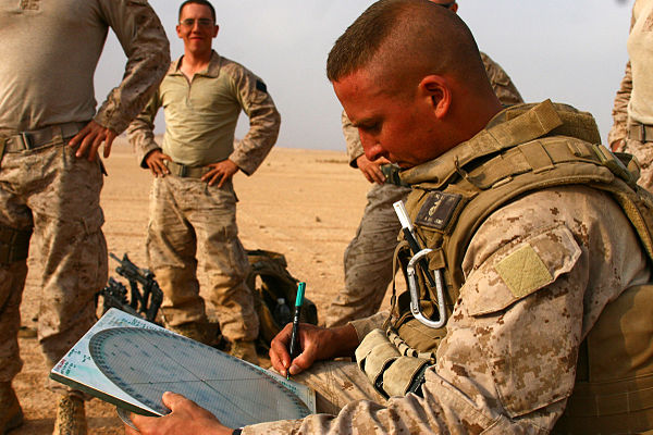 A United States Marine lance corporal plots the direction and elevation of a mortar before firing.