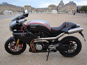 Black and silver streamlined motorcycle in foreground with a French palace backdrop