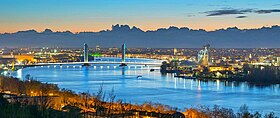 Vue large de la ville éclairée de nuit, avec le pont Jacques Chaban-Delmas en fond.