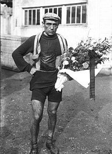 Zwart-witfoto van een man in wielrenneroutfit met een bos bloemen in zijn linkerhand.