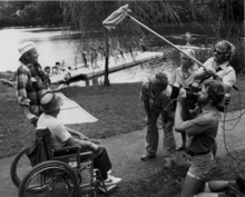 On location outside Baltimore, cameraman Jim Furrer, sound recordist Bill Porter, and director David Ryan interview participants in a public rowing clinic as part of an early electronic journalism shoot in the 1980s. Electronic journalism crew shooting interview on location.png