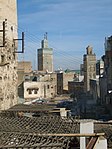 Una imagen de un callejón trasero iluminado por el sol con basura esparcida por el área.  Varios edificios de diversa arquitectura son claramente visibles.