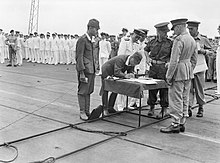 The formal surrender of Japanese forces at Rabaul on 12 September 1945 General Imamura signing the official document of surrender for Japanese forces in New Britain, New Ireland, the Solomons and New Guinea, on the flight deck of HMS GLORY off Rabaul, 12 September 1945. A30498.jpg