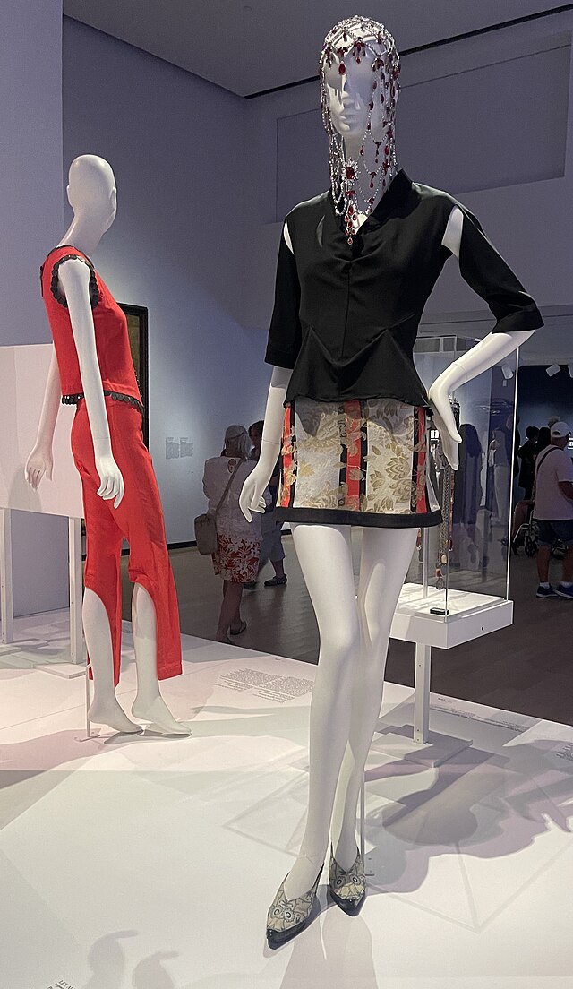 Left: red two-piece outfit shown from the side. Right: frontal view of two-piece outfit with black top and gold, red, and black striped miniskirt.